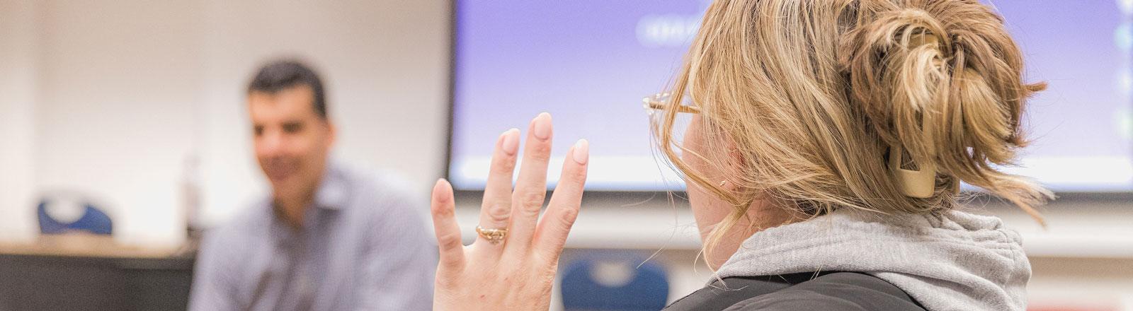 Student raising a hand to answer a question in class.